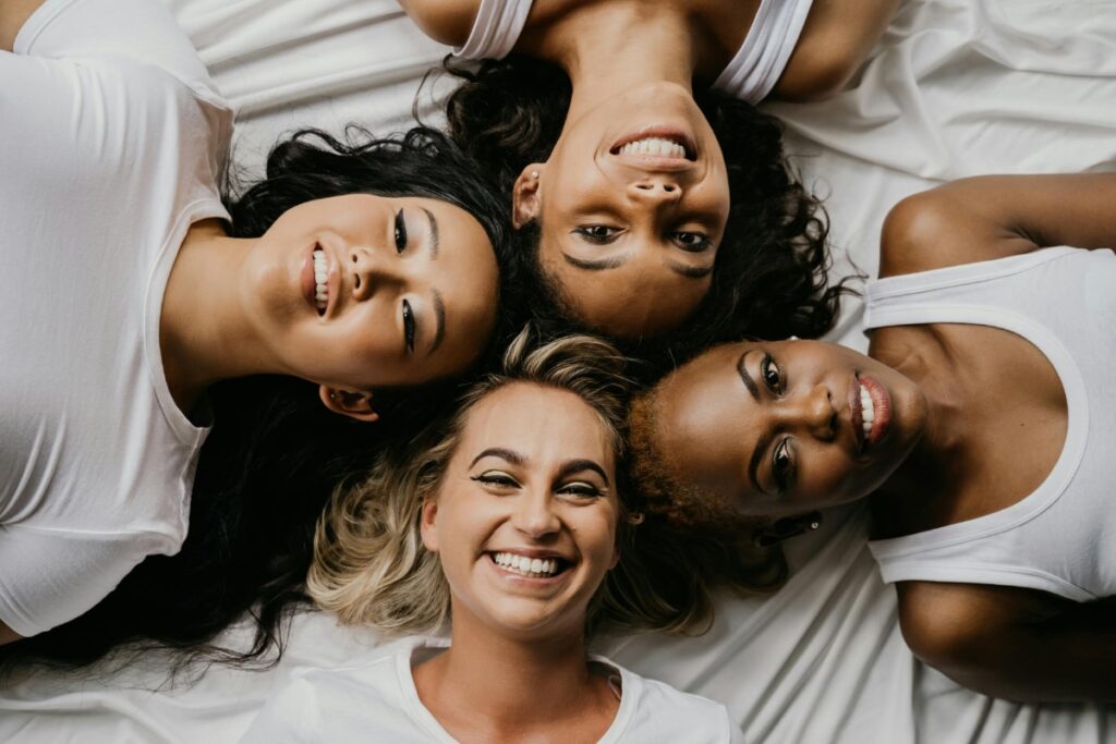 A group of 4 diverse woman all smiling up